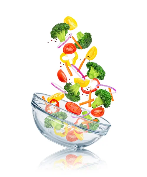 Vegetables falling into a glass bowl on a white background. Conc — Stock Photo, Image