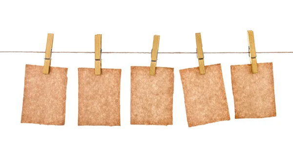 Kraft papír visí od clothespins na izolované bílém pozadí — Stock fotografie