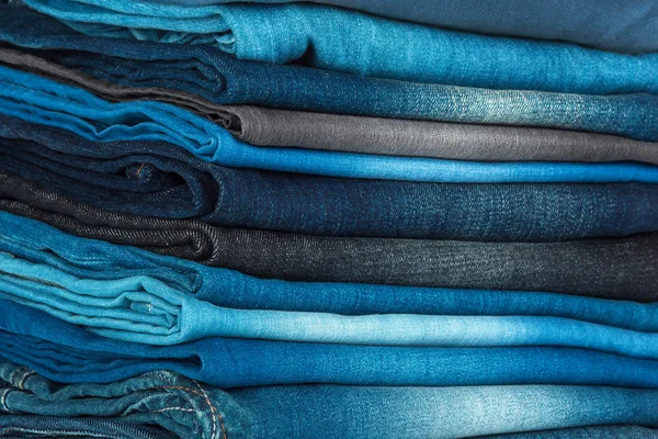 Pilha de diferentes tons de calça azul como fundo — Fotografia de Stock