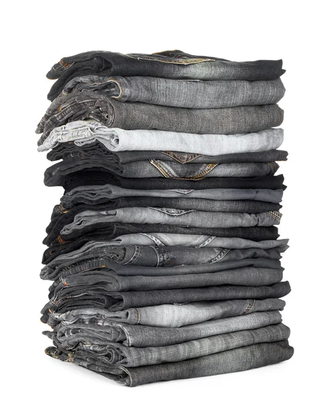 Высокая стопка джинсов серый и черный на белом фоне — стоковое фото