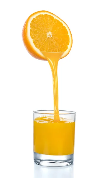 Frischer Orangensaft fließt aus geschnittener Orange ins Glas. isoliert auf weißem Hintergrund. — Stockfoto