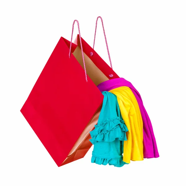 Червона торгова сумка з різнокольоровим одягом, що падає в повітрі. зачаття — стокове фото