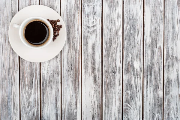 Taza de café y granos de café sobre fondo de madera — Foto de Stock