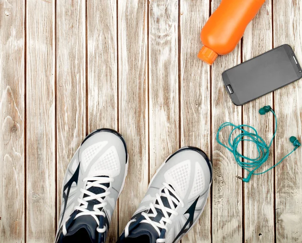 Equipamiento deportivo. Zapatillas, agua, auriculares y teléfono en madera —  Fotos de Stock