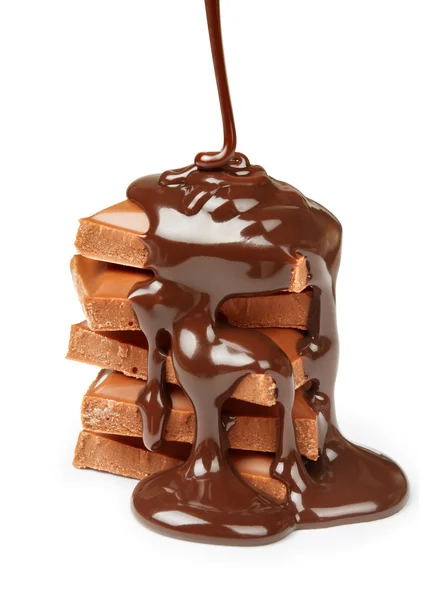 Schokoladensirup wird isoliert auf Schokoladenstücke gegossen — Stockfoto