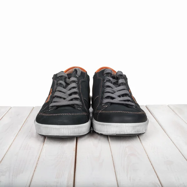 Coppia di sneakers nere su sfondo bianco in legno — Foto Stock