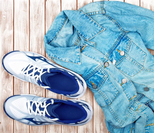 Sneakers and denim shirt on a wooden background — Stock Photo, Image