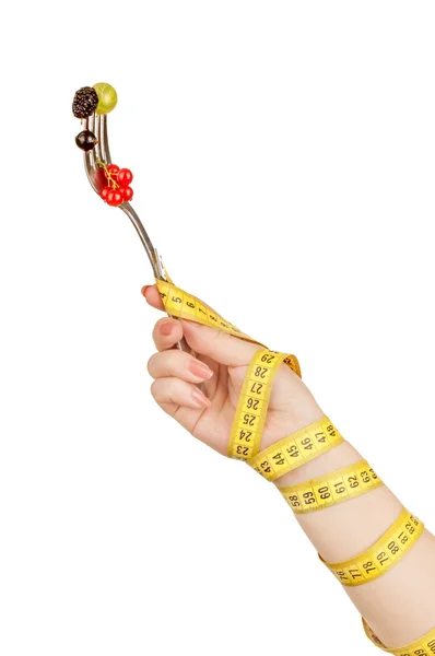 Hand wrapped with measuring tape holding a fork with berries — Stock Photo, Image