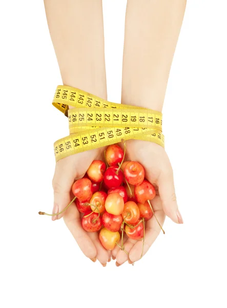 Mãos amarradas com fita métrica segurando cerejas — Fotografia de Stock