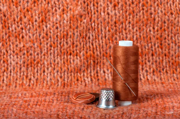 Needle with thread and buttons on a fabric background — Stok fotoğraf