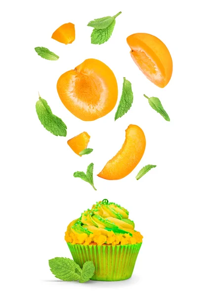 Cupcake with flying pieces of apricot and mint isolated on white — Stock Photo, Image