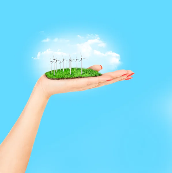 Turbinas eólicas no prado detém na mão das mulheres contra o céu azul — Fotografia de Stock