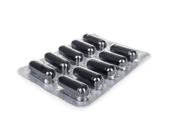 Black capsules in the package isolated on a white background — Stock Photo, Image