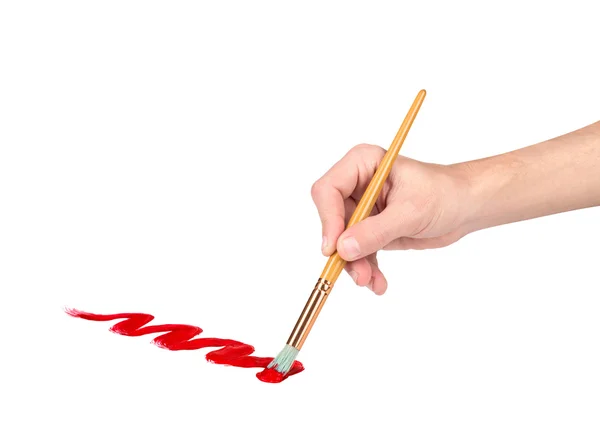 Mão com uma escova desenha linha vermelha em um fundo branco isolado — Fotografia de Stock