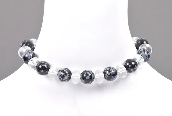 Rock crystal and snowflake obsidian chain on bust — Stock Photo, Image