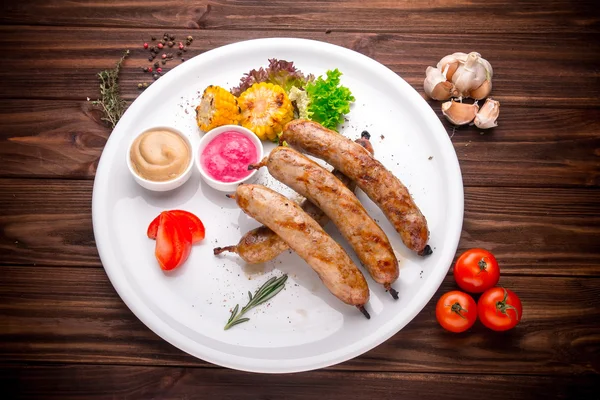 Embutidos a la parrilla con verduras y condimentos en madera —  Fotos de Stock