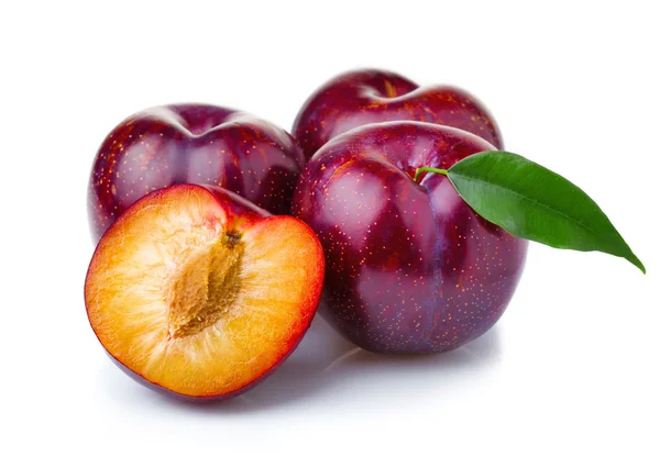 Ripe purple plum fruits with green leaves isolated on white — Stock Photo, Image