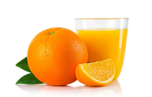 Glas mit Orangensaft und Früchten mit grünen Blättern lizenzfreie Stockfotos