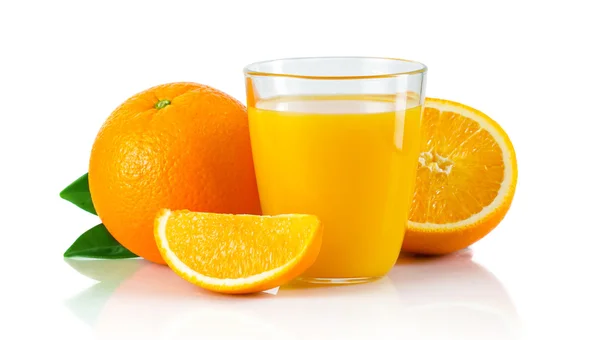 Glas mit Orangensaft und Früchten mit grünen Blättern Stockbild