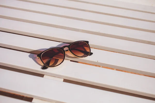 Sluneční brýle ležet na slunci lehátko dřevo — Stock fotografie