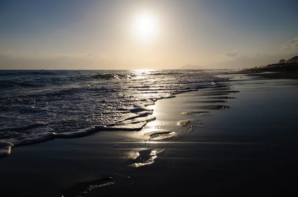 Vestígios em areia molhada em uma praia de tarde . Fotos De Bancos De Imagens