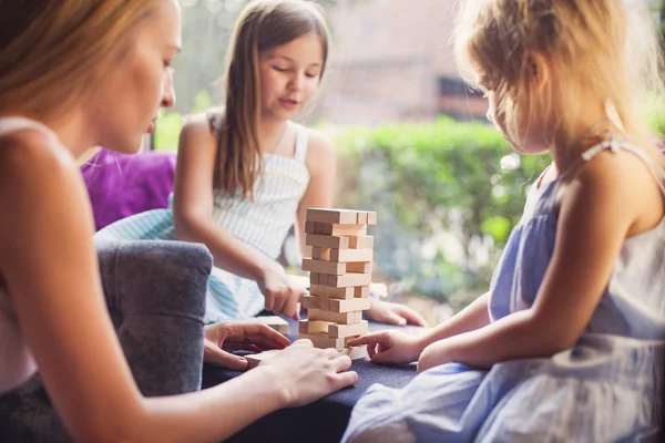 Mãe feliz com duas crianças jogando a torre de blocos de madeira — Fotografia de Stock