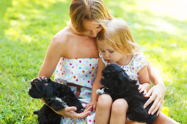 Petite fille mignonne et sa mère étreignant chiots chien — Photo