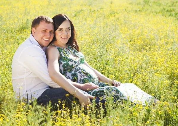 Jovem casal grávida feliz no parque de primavera florido — Fotografia de Stock