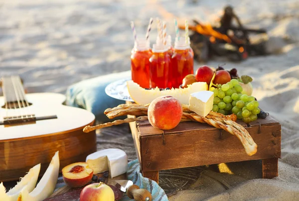 Piknik na plaży o zachodzie słońca z owoców i soków — Zdjęcie stockowe