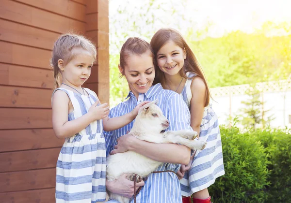 Feliz madre y sus hijas con cabras bebé — Foto de Stock