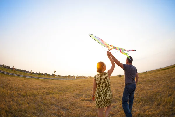 Pareja feliz enamorada de volar una cometa — Foto de Stock