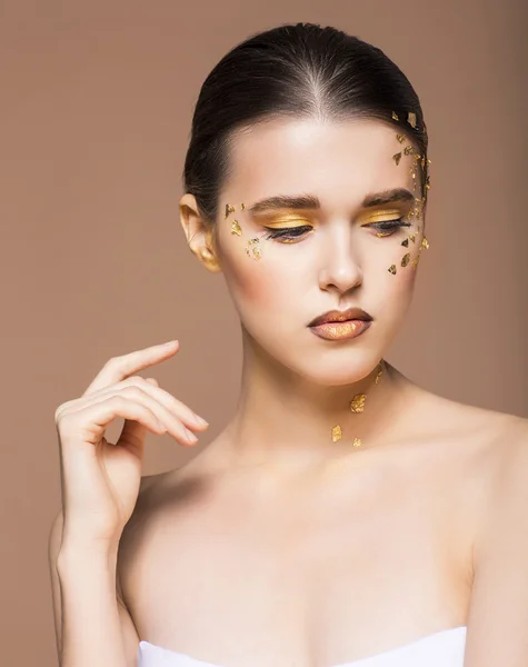 Retrato de uma bela jovem com maquiagem dourada brilhante — Fotografia de Stock