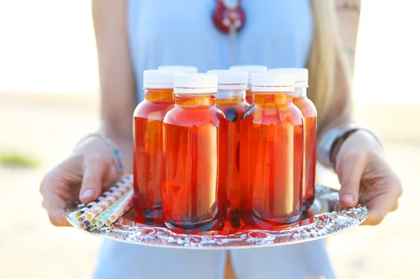 Happy young woman holding a dish with a drinks at sunset party — Stock Photo, Image