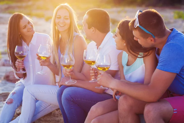 Persone che tengono bicchieri di vino bianco al picnic in spiaggia — Foto Stock