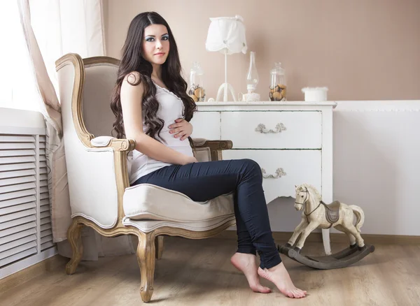 Gravid kvinna sitter i fåtölj, inomhus — Stockfoto