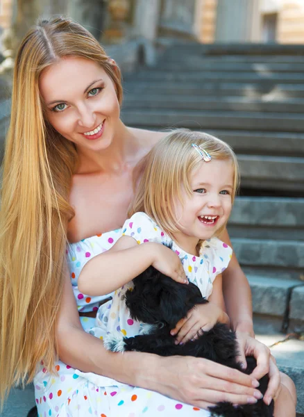 Petite fille mignonne et sa mère étreignant chiots chien — Photo