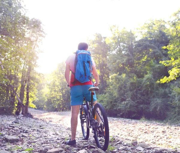 Athlete man crossing mountain river with bicycle — Stock Photo, Image