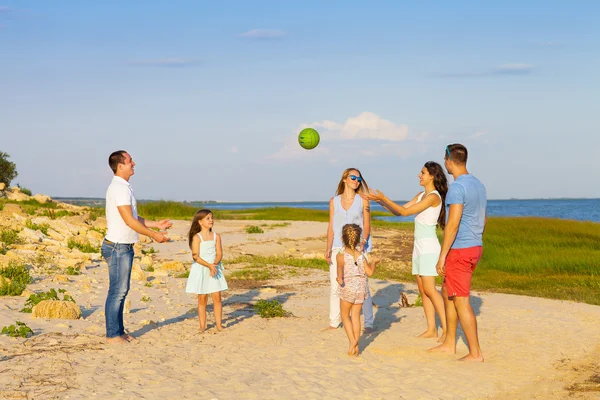 Vrienden met kinderen die spelen met de bal op het strand — Stockfoto