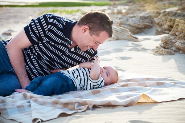 Unga far leker med barnet anses ligga på stranden, — Stockfoto