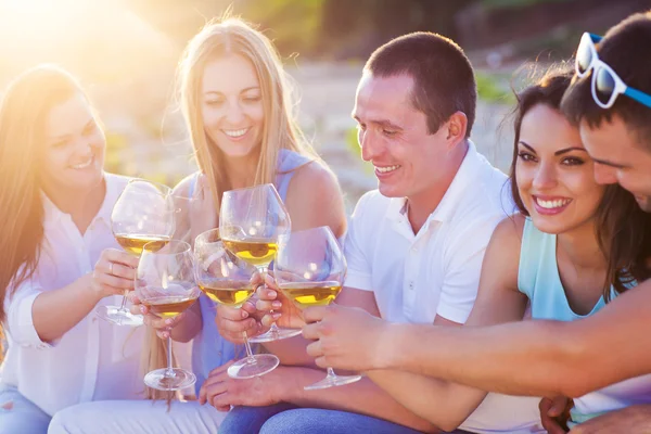 Gente sosteniendo copas de vino blanco haciendo un brindis en la playa — Foto de Stock