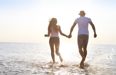 Mutlu genç çift eğleniyor kumsalda günbatımında çalışan
