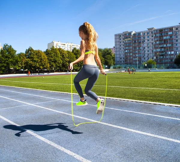 Young woman with a jumping rope in her hands with a stadium as b — Stock Photo, Image