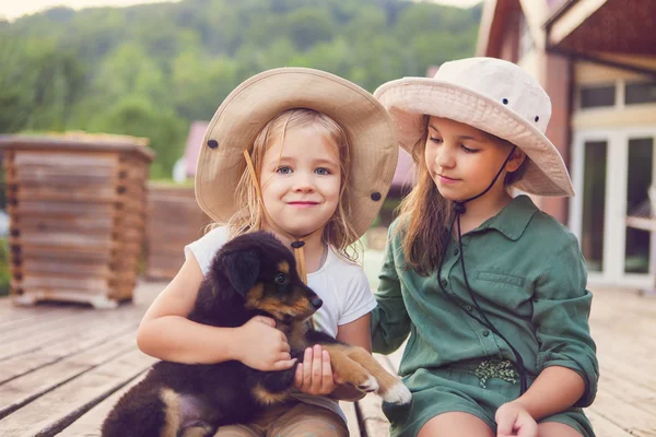 Дві милі маленькі сестри обіймають цуценя собаки — стокове фото