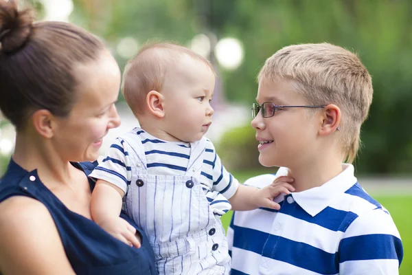 Glad mamma och hennes barn leker i parken tillsammans — Stockfoto