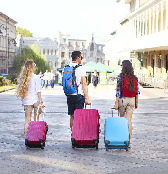 Vrienden van de reizigers met bagage lopen door de straat van de stad — Stockfoto