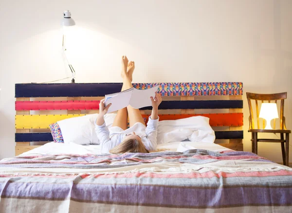 Mulher feliz lendo uma revista na cama — Fotografia de Stock