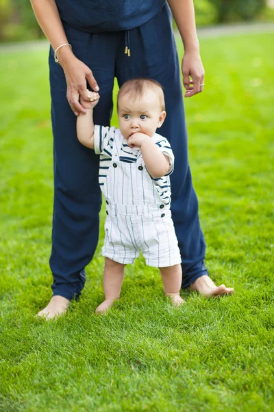 Barnet lära sig gå utomhus. Glad mamma och hennes son spelar — Stockfoto