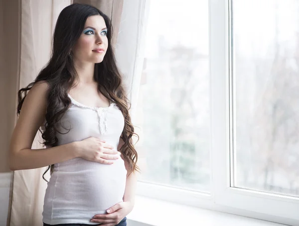 Schwangere steht am Fenster — Stockfoto