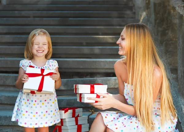 Schattig klein meisje en haar moeder bedrijf presenteert — Stockfoto