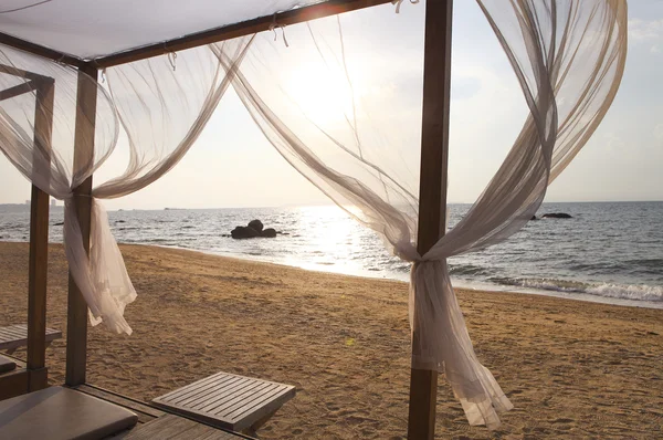 View of a beach in sunset through the curtains of a beach bed — Stock Photo, Image